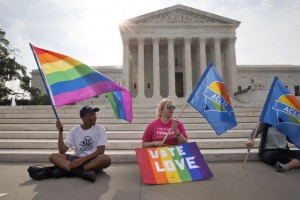 Carlos McKnight, 17, of Washington, left, and Katherine Nicole Struck, 25, of Frederick, Md., hold flags in support of gay marriage outside of the Supreme Court in Washington, Friday June 26, 2015. A major opinion on gay marriage is among the remaining to be released before the term ends at the end of June. (AP Photo/Jacquelyn Martin)